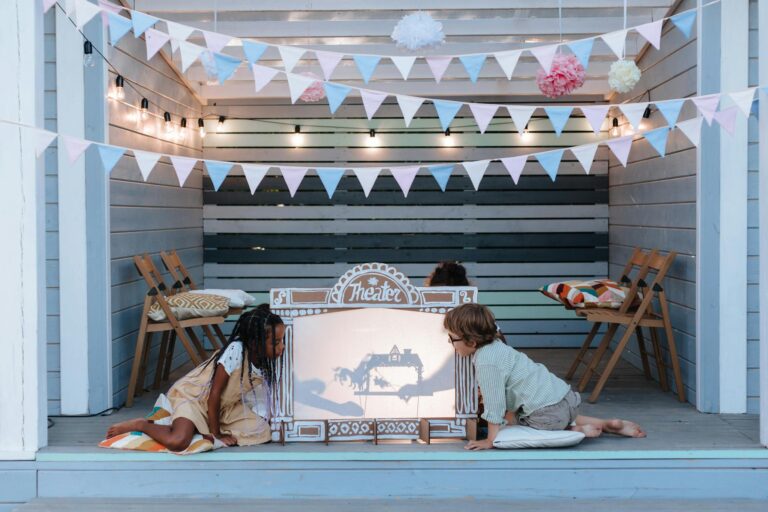 Children engage in creative puppet play at an indoor shadow theater with festive decorations.