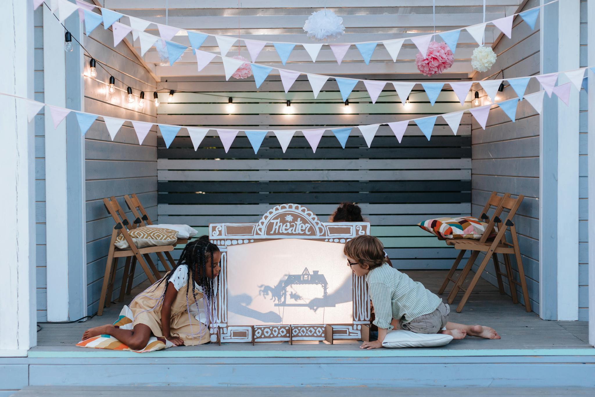 Children engage in creative puppet play at an indoor shadow theater with festive decorations.